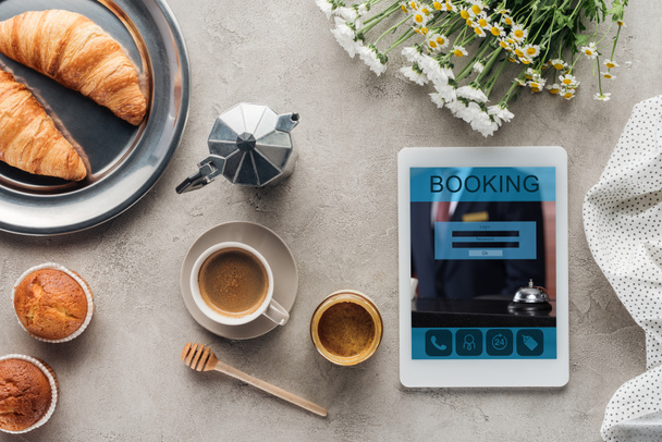 pohled shora kávy s pečivo a tablet s aplikací rezervace na obrazovce na betonový podklad - Fotografie, Obrázek