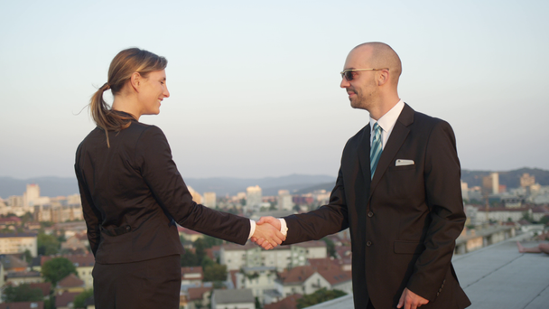 SLOW MOTION CLOSE UP DOF: Businessman successfully accomplishing commercial deal shaking hands with female representative of corporate financial company on top of office building with stunning view - Footage, Video