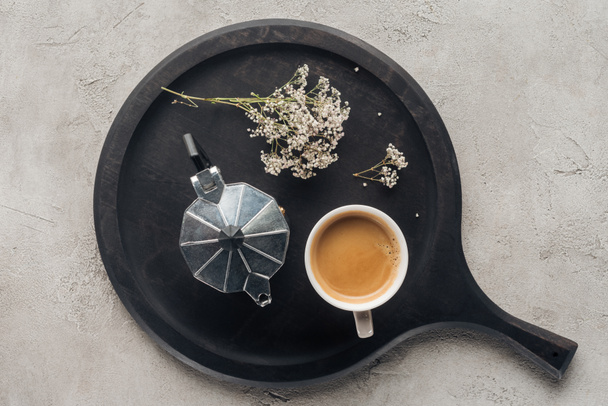 top view of cup of delicious coffee and moka pot with field flowers on concrete surface - Photo, Image