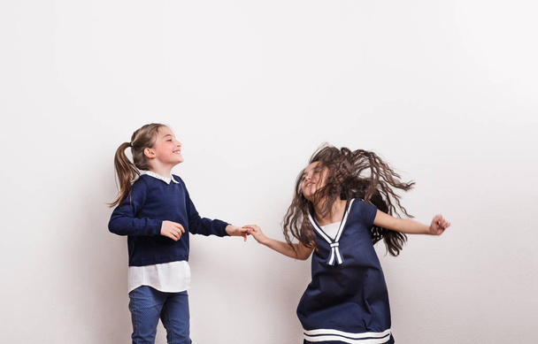 Two small girls in a studio, holding hands, having fun. - Fotografie, Obrázek