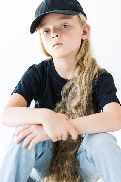 portrait of beautiful child with long curly hair wearing black cap and looking at camera isolated on white - Foto, Imagem