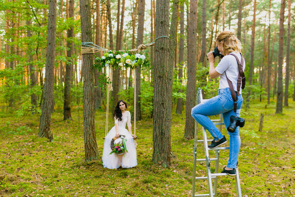 Professional wedding photographer using stepladder to make pictures of the bride - Foto, imagen