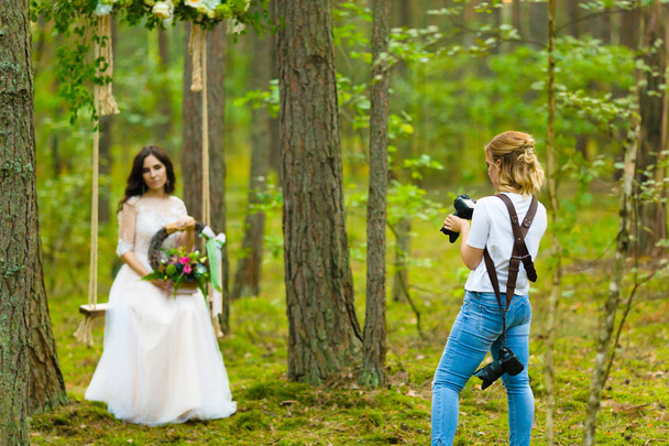 Wedding photographer taking pictures of the bride on a rope swing - Foto, imagen