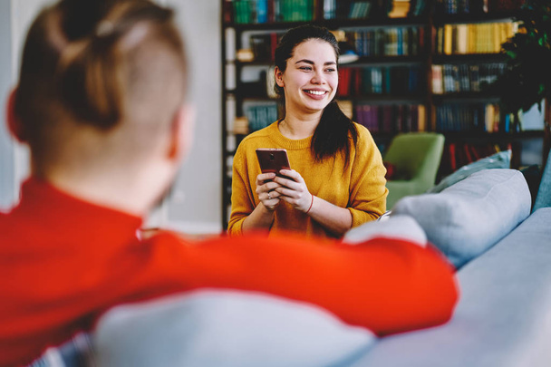 Cheerful woman sitting with smartphone at home interior get message with good news, happy hipster girl spending time with boyfriend at apartment satisfied with wireless connection for networkin - Foto, immagini