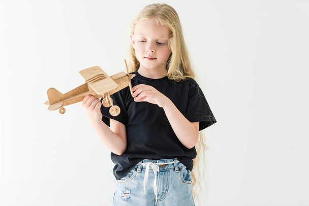 piękne małe dziecko bawi się drewniana zabawka samolot na białym tle  - Zdjęcie, obraz