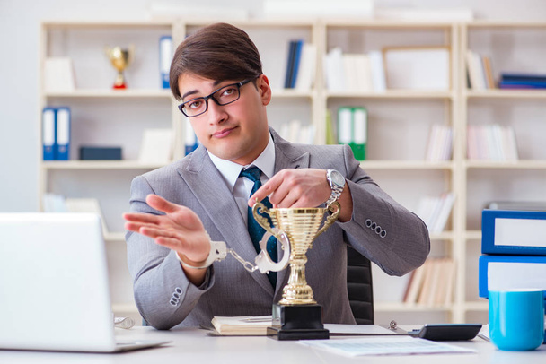 Бизнесмен с золотой чашкой в офисе - Фото, изображение
