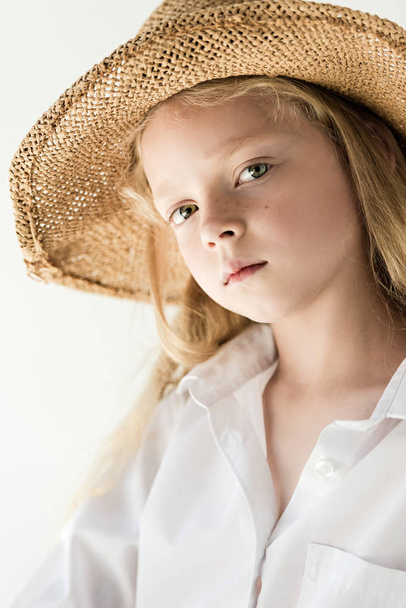 портрет красивої маленької дитини в плетеному капелюсі дивиться на камеру на білому
 - Фото, зображення