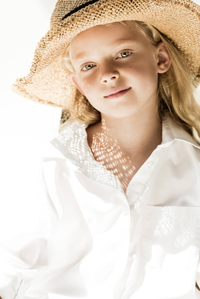portrait of adorable little child in wicker hat smiling at camera on white - 写真・画像