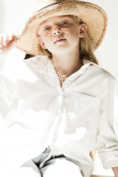 portrét roztomilé malé dítě v slamák na bílém při pohledu na fotoaparát  - Fotografie, Obrázek