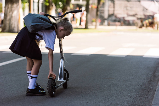 takaisin näkymä söpö pieni lapsi reppu vahvistamisesta skootteri kadulla
 - Valokuva, kuva
