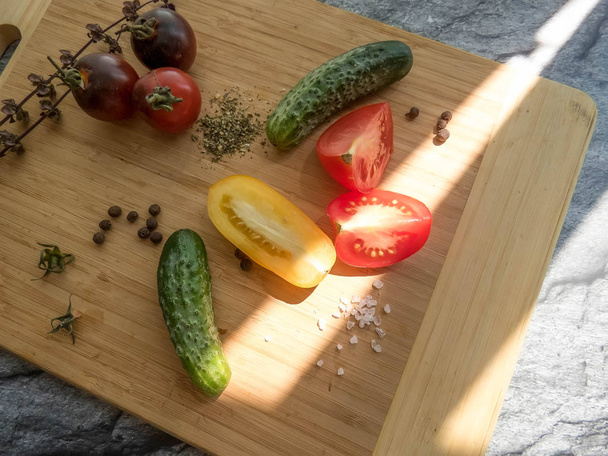 tomates rojos y amarillos en rodajas y pepino en una tabla de madera. una alimentación saludable. productos ecológicos. Comida orgánica. Estilo Top View Group Objetos
 - Foto, Imagen