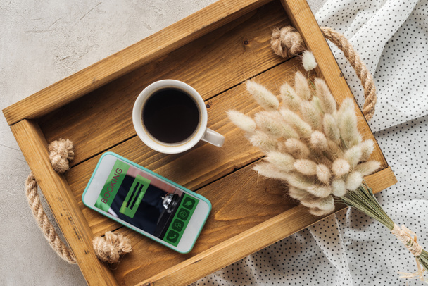 felülnézet csésze kávé és smartphone-val weboldal foglalás képernyőn a tálca lagurus ovatus csokor a betonfelület - Fotó, kép