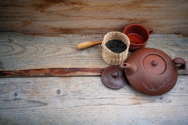 clay Chinese teapot on a wooden stand on an old board - Photo, image
