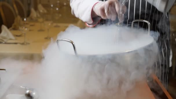 Cooking in restaurant. Cooker at work. Proffessional chef in gloves cooks dessert with dry ice. Chef pours water into bowl with dry ice. Slow motion. - Footage, Video