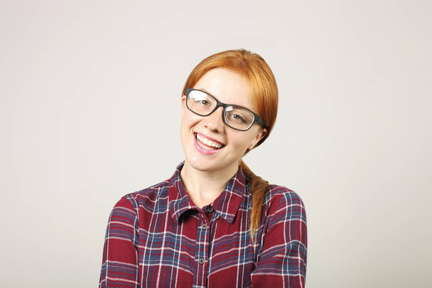 Close up portrait of beautiful young woman college student w/ red hair wearing black frame eye glasses & flannel shirt. Redhead female smiling. Redhead female in casual outfit. Background, copy space. - Фото, зображення