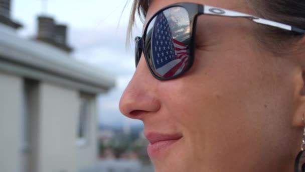 FECHAR, SLOW MOTION: Bandeira americana colorida acenando ao vento e refletindo nos óculos de sol da jovem. Orgulhoso cidadão americano e patriota apoiando partido político, nação, cultura e liberdade
 - Filmagem, Vídeo