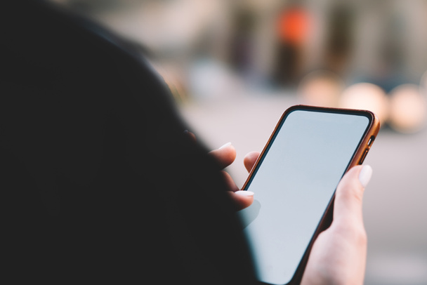 abgeschnittene Ansicht einer jungen Frau, die ein modernes Smartphone in der Hand hält und Textnachrichten auf dem Display eines digitalen Gerätes tippt. - Foto, Bild