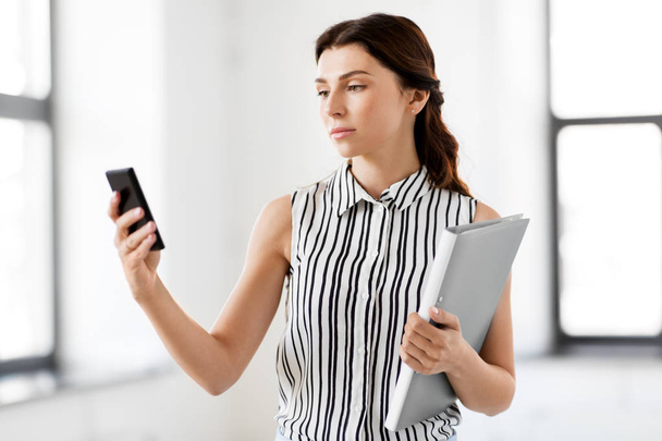 businesswoman with smartphone and folder at office - Fotoğraf, Görsel