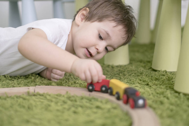 Egy színes gyerek szoba egy óvoda vagy óvodai kis kisgyermek. gyermek fiú játék-val toys mutatók otthon. Ázsiai baby 2 éves, egyedül játszik a zöld szőnyeg. - Fotó, kép