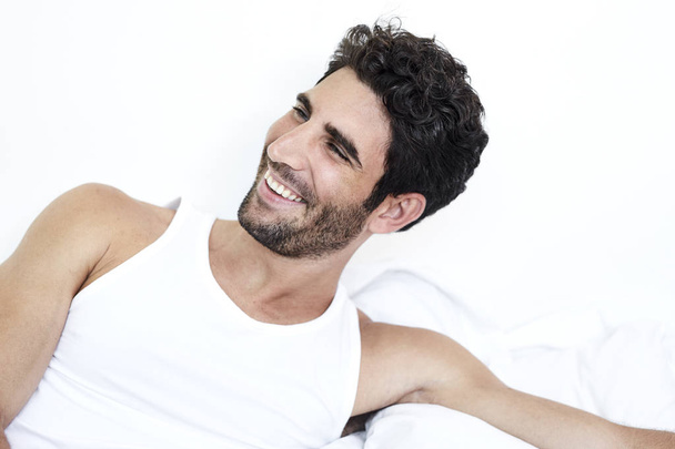 Smiling man in bed, looking away - Foto, imagen