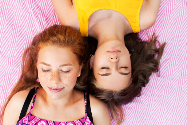 teenage girls lying on picnic blanket - Фото, изображение
