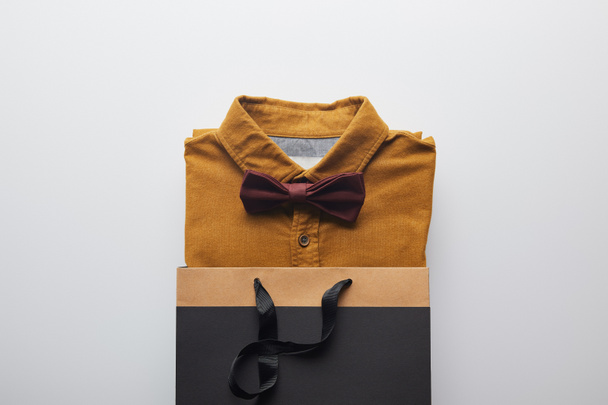 top view of new brown shirt and bow tie in shopping bag isolated on white - Valokuva, kuva