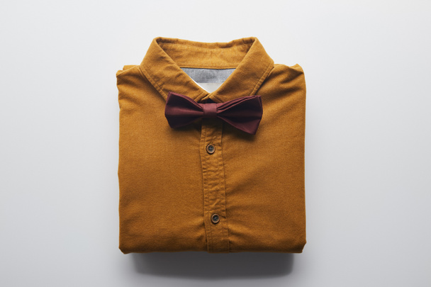 top view of brown shirt and bow tie on white - 写真・画像