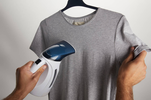 cropped image of man ironing grey shirt on hanger isolated on white - Foto, Imagen