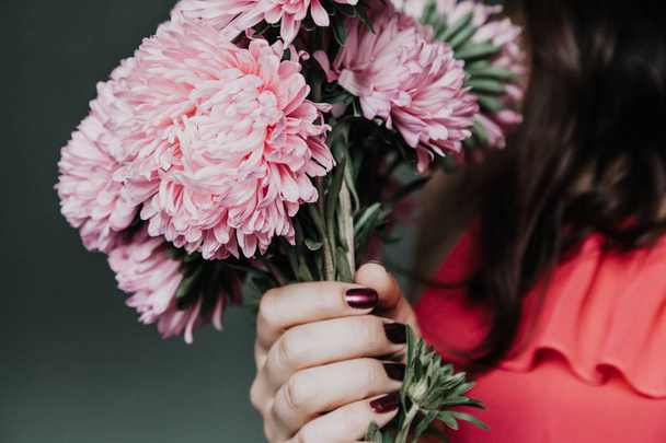 chica en un vestido rojo está sosteniendo un ramo de crisantemo rosa
 - Foto, Imagen