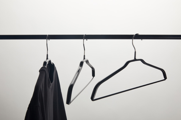 black shirt and empty hangers on stand isolated on white - Photo, Image