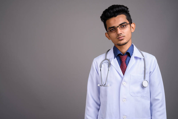 Nuori intialainen mies lääkäri harmaata taustaa vasten
 - Valokuva, kuva