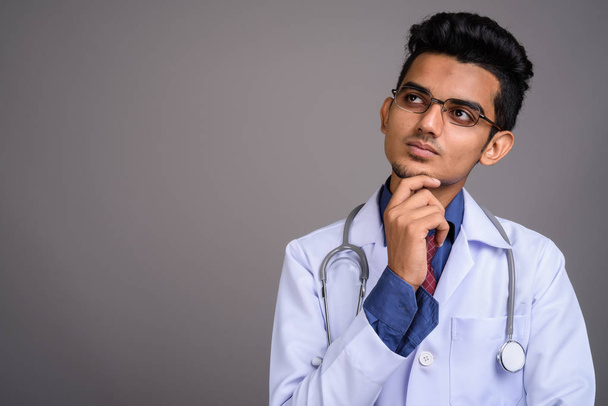 Молодой индийский врач на сером фоне
 - Фото, изображение