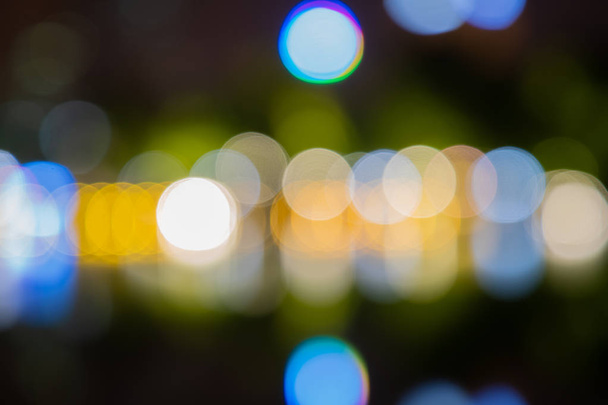 Bokeh abstracto de verde, amarillo, rojo, azul en las luces de la calle fondo negro. Vida nocturna y reflexionar sobre el agua
. - Foto, Imagen