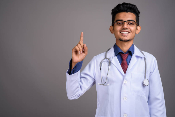 Young Indian man doctor against gray background - Fotó, kép