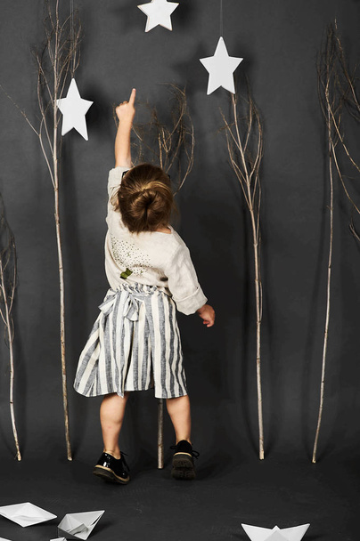 menina com óculos no fundo cinza com estrelas, árvores e barcos de papel
 - Foto, Imagem