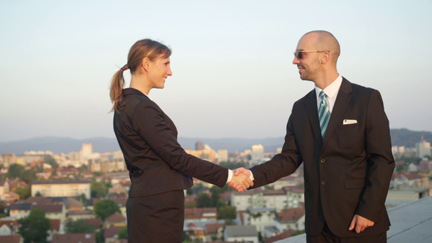 SLOW MOTION CLOSE UP DOF: Businessman successfully accomplishing commercial deal shaking hands with female representative of corporate financial company on top of office building with beautiful view - Footage, Video