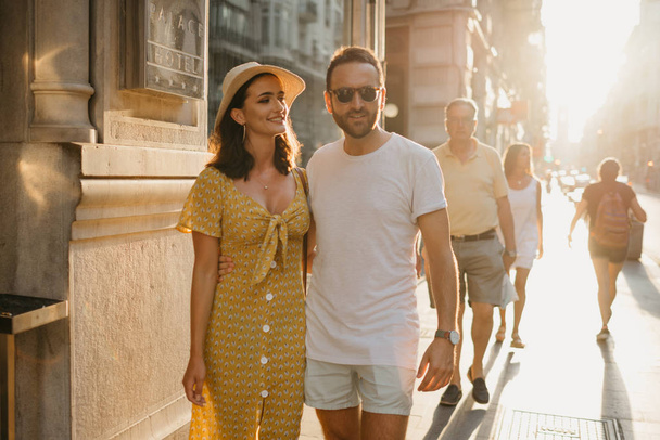 Awesome brunette girl with her boyfriend with beard standing together on the old European street in Spain on the sunset - Fotó, kép