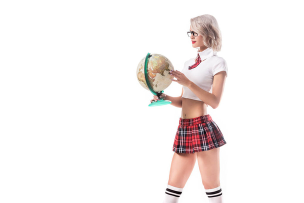 sexy blond woman in eyeglasses and college uniform holding globe isolated on white - Фото, зображення