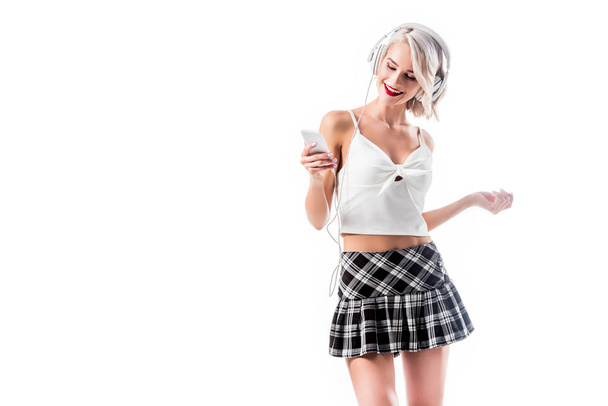 portrait of seductive schoolgirl with smartphone listening music in headphones isolated on white - Zdjęcie, obraz