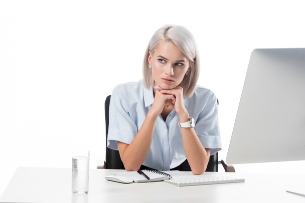портрет задумчивой деловой женщины на рабочем месте со стеклом воды, ноутбуком и экраном компьютера, изолированным на белом
 - Фото, изображение