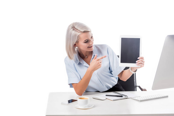 portrait of smiling businesswoman pointing at tablet with blank screen at workplace isolated on white - Photo, Image