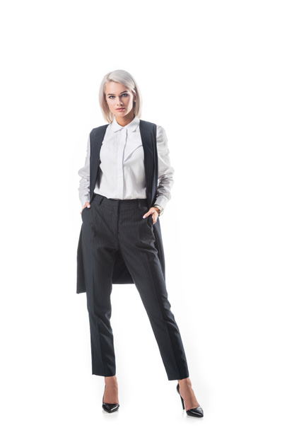 jovem mulher de negócios elegante em desgaste formal com as mãos em bolsos isolados em branco
 - Foto, Imagem