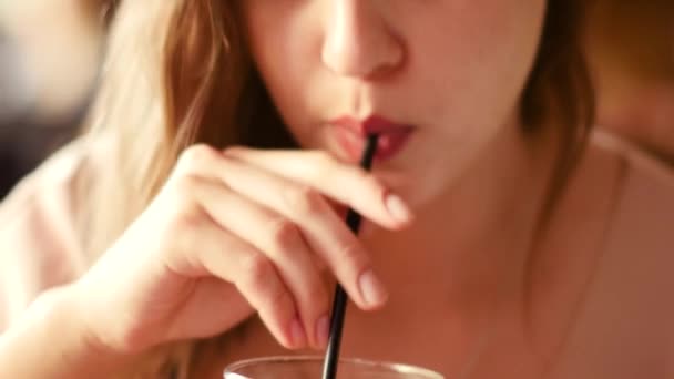 A beautiful woman with a smartphone in her hand drinks a cocktail at the bar - Video
