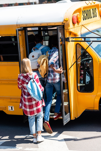 rear view of teen students walking into school bus - Foto, Imagen