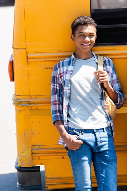 happy teen african american schoolboy leaning back on school bus - Fotografie, Obrázek