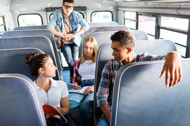 group of teen scholars riding school bus and spending time together - Photo, Image