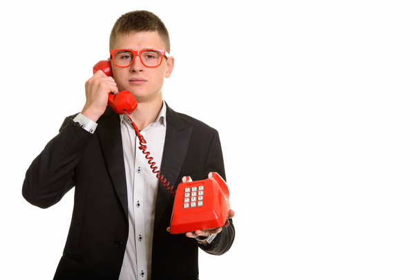 Studio shot of young businessman talking on old telephone - 写真・画像