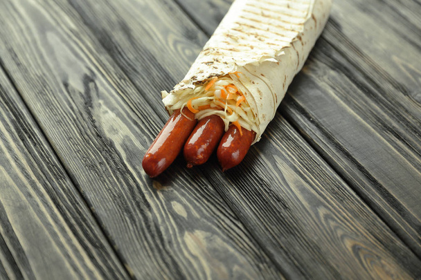 spicy sausages in pita bread on wooden background - Foto, imagen