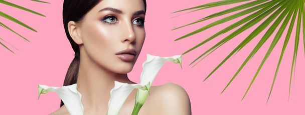 Spa vrouw met gezonde huid, witte bloemen en tropische laat op roze achtergrond, Wellness schoonheid en gezichtsbehandeling - Foto, afbeelding
