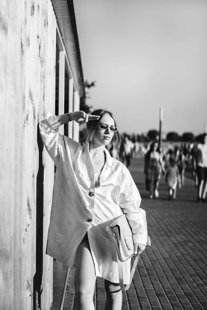Monochrome portrait of stylish woman posing outdoor near wooden wall. - Foto, Imagen